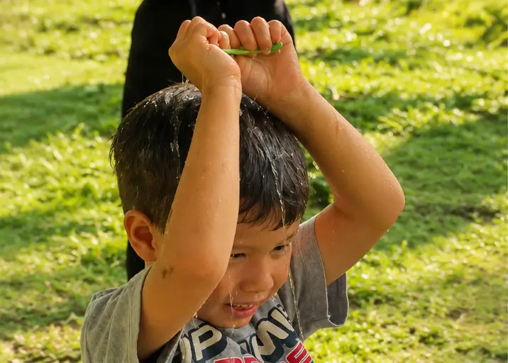 Kids Water Play Activity Outdoors Child enjoying outdoor water play activity on a sunny grassy field in Bali
