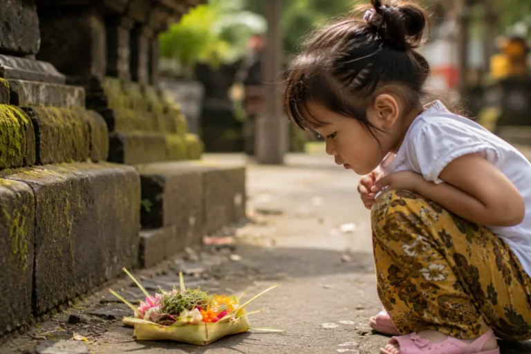 A young child curiously observing a traditional Canang Sari offering beside a temple pathway in Bali